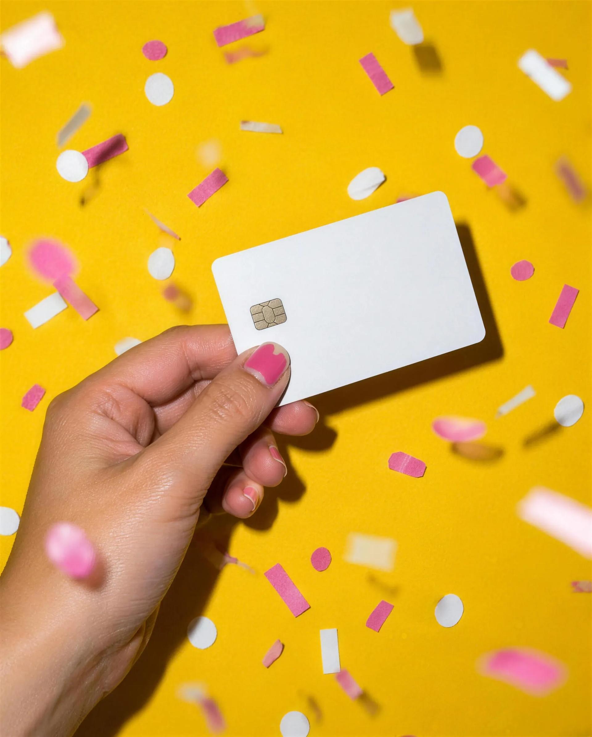 A hand holding a card in a burst of confetti