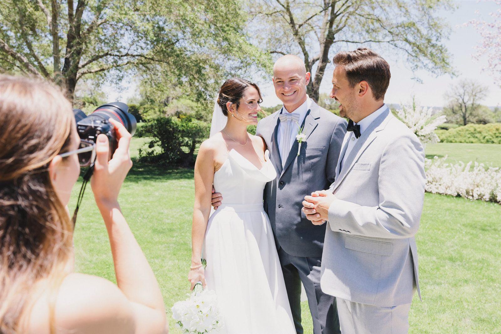 A wedding photographer sharing photos with a couple outdoors