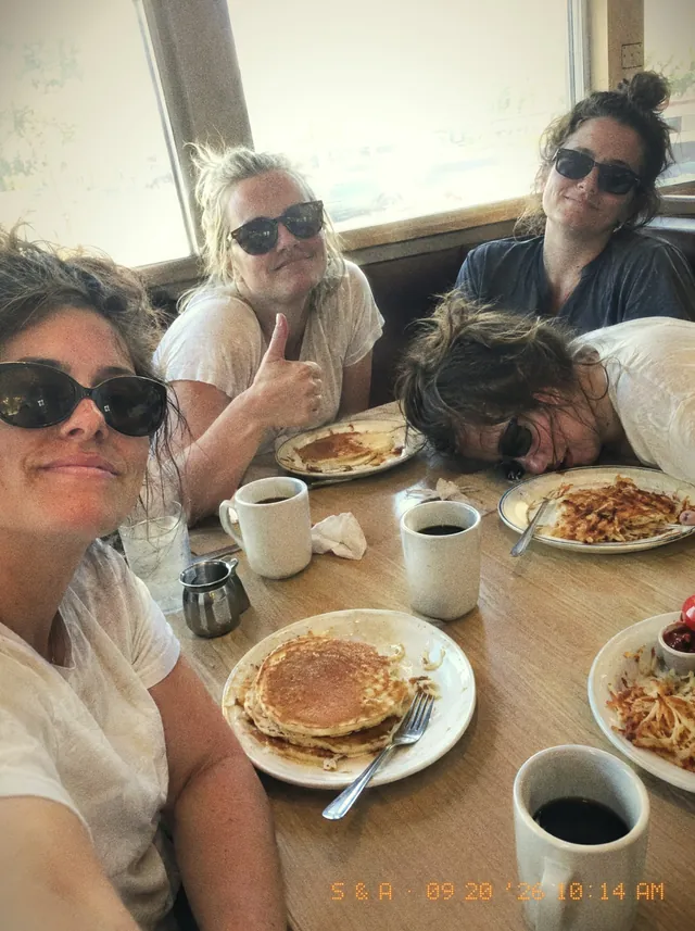The morning after at a diner: pancakes, coffee, sunglasses on, one friend with her head down on the table.