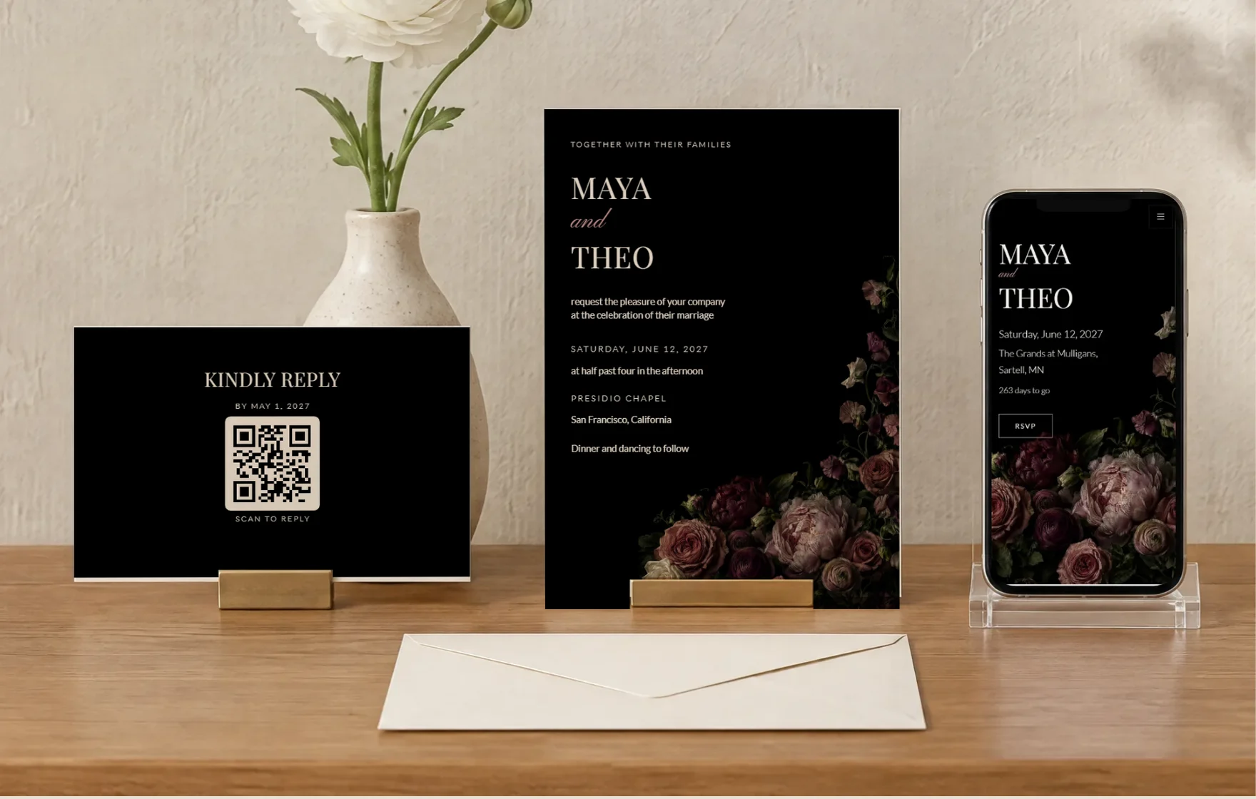 An invitation and a reply card in brass holders on an oak sideboard, beside a phone showing the same design as a wedding website